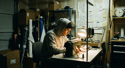 Young entrepreneur in a cluttered, converted garage workshop at 3 AM.